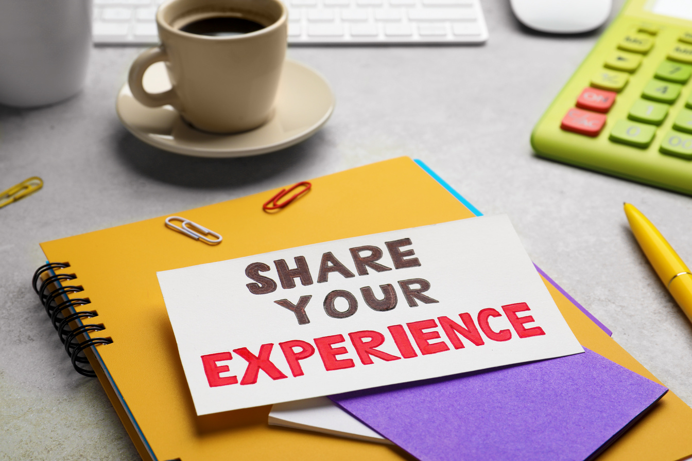 Share Your Experience. Workplace with Card and Stationery on Lig